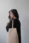female model wearing  the large aura backpack in beige Horween dearborn leather