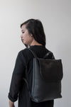 front view of the large ray backpack in black pebbled leather with a veg tan flap