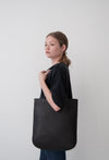 female model wearing the emit tote in black Horween essex veg tan leather